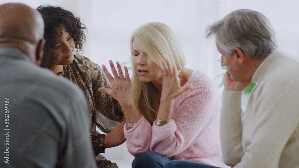 Group sitting in a circle at support meeting as mature woman discusses issues affecting her - shot in slow motion Group sitting in a circle at support meeting as mature woman discusses issues affecting her - shot in slow motion