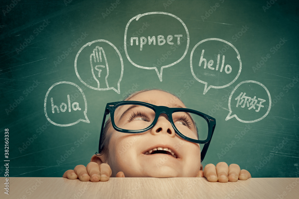 Beautiful cute little girl with eyeglasses looking at hello word in