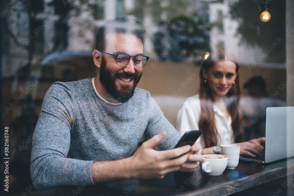 Fototapeta premium Man messaging on phone meeting with female in cafe
