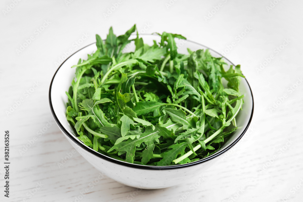 Fresh arugula in bowl on white wooden table Fresh arugula in bowl on white wooden table