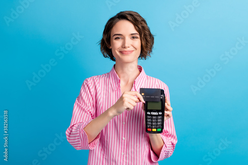 Photo of positive lady swipe credit card on pos terminal wear formal white pink clothes isolated over blue color background photo