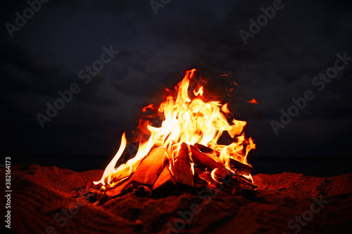 Beautiful bonfire with burning firewood on beach at night