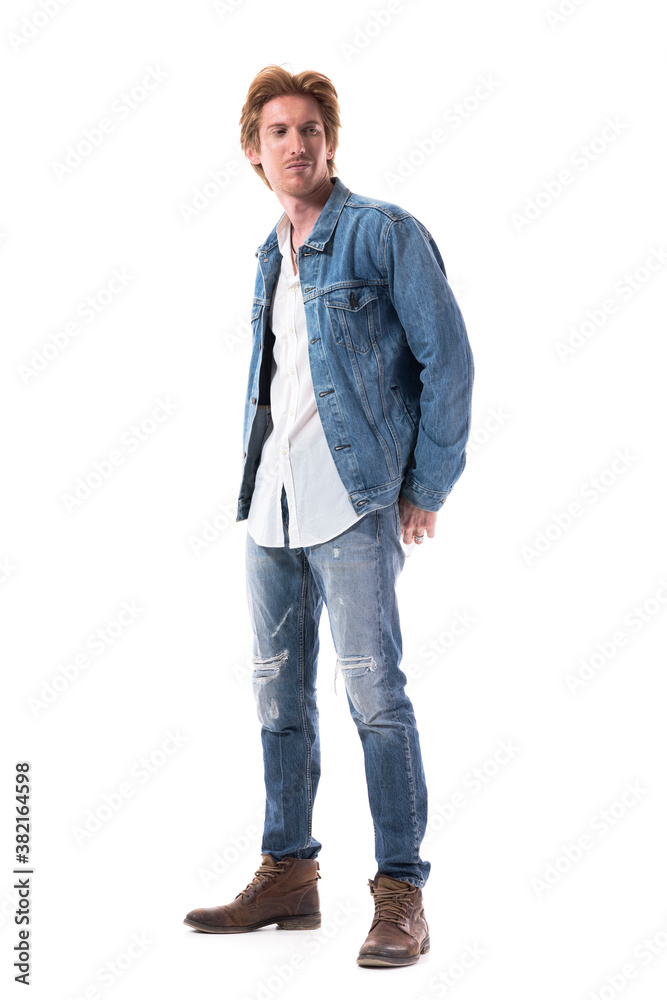 Naklejka premium Satisfied young stylish man in jeans looking back over shoulder and smirk smiling. Full body isolated on white background.