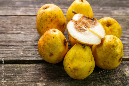 Group of rotting pears  focus on the half cutted fruit on aged weathered pine wood boards.