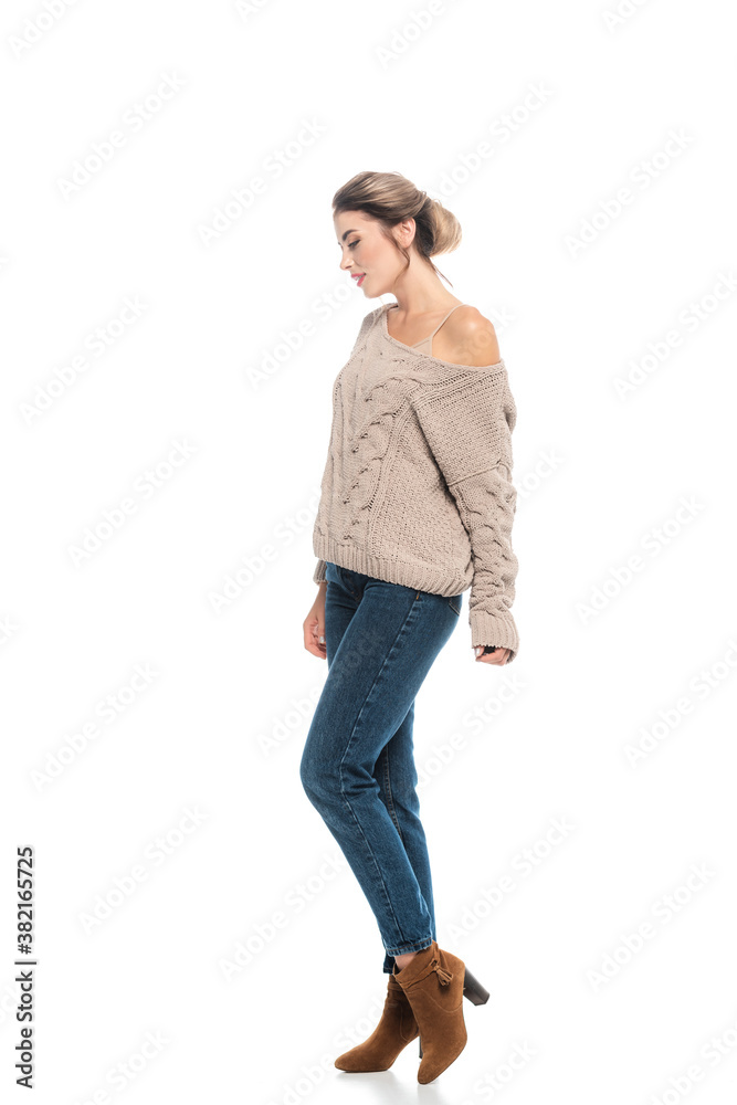 full length view of fashionable woman in openwork sweater and jeans posing on white full length view of fashionable woman in openwork sweater and jeans posing on white