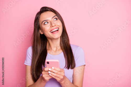 Portrait of funky young woman hold phone wear casual look empty space isolated on pink color background