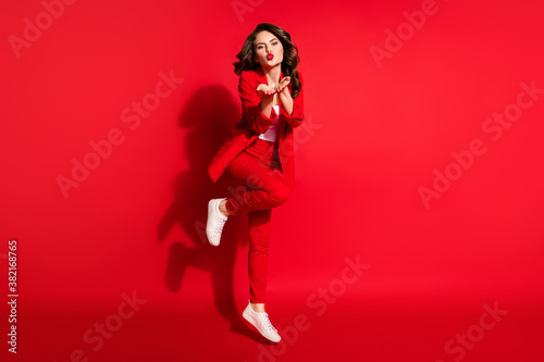 Full length photo of cute young girl jump send you air kiss bright pomade wear blazer trousers footwear isolated red color background © deagreez
