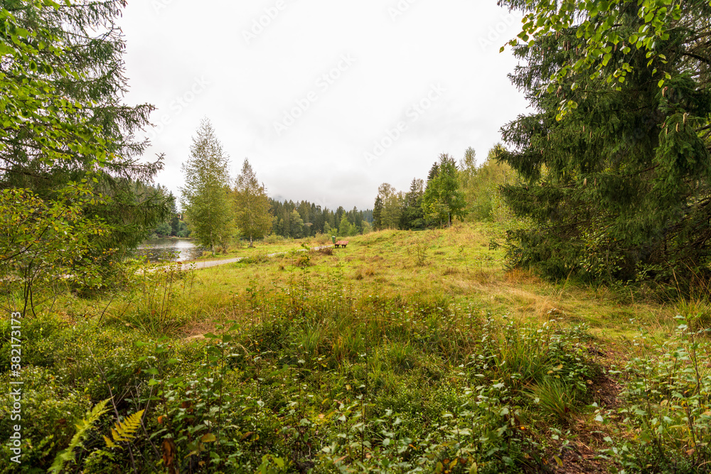 Fototapeta premium Rundweg am Schwarzsee bei Kitzbühel in Tirol bei Regen und Wolken