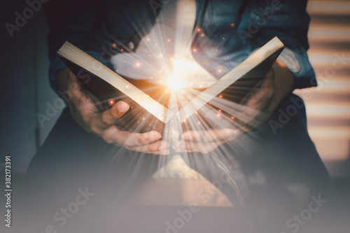 The light coming from the book in the hand of man concept wisdom religion reading imagination. photo