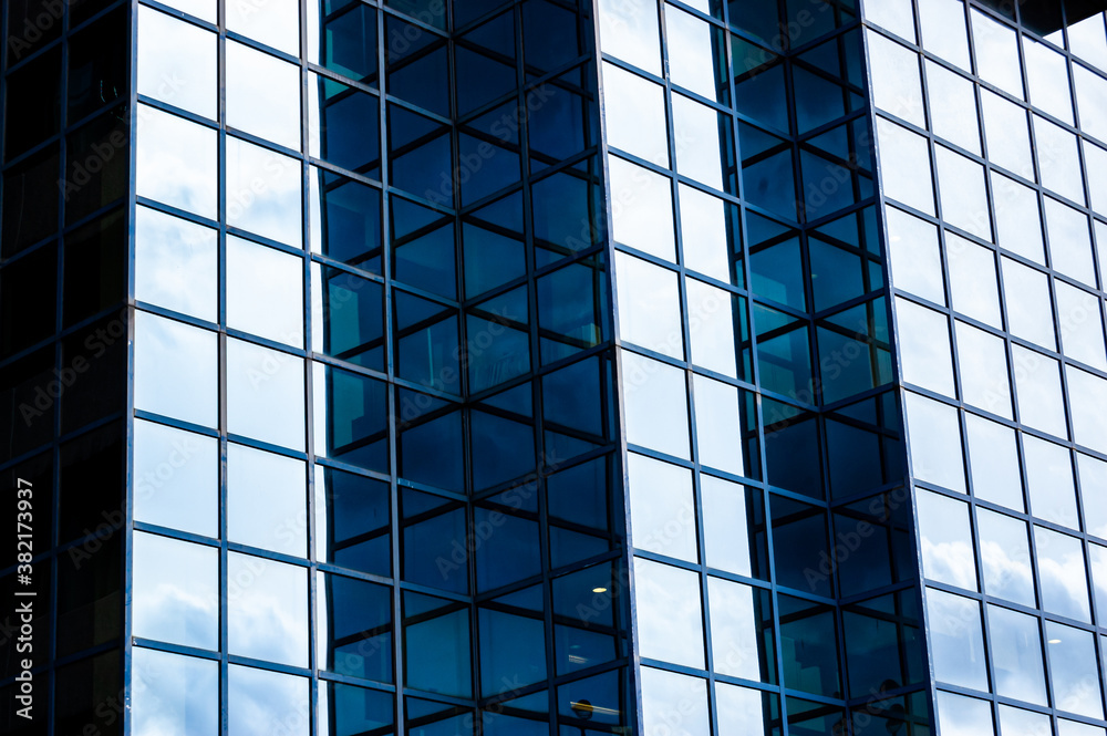 Fototapeta premium Contemporary blue glass and metal facades of skyscrapers full of offices. Cornered exterior design playing with light and shadow.