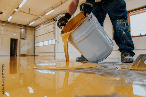 Worker applying a yellow epoxy resin bucket on floor. photo