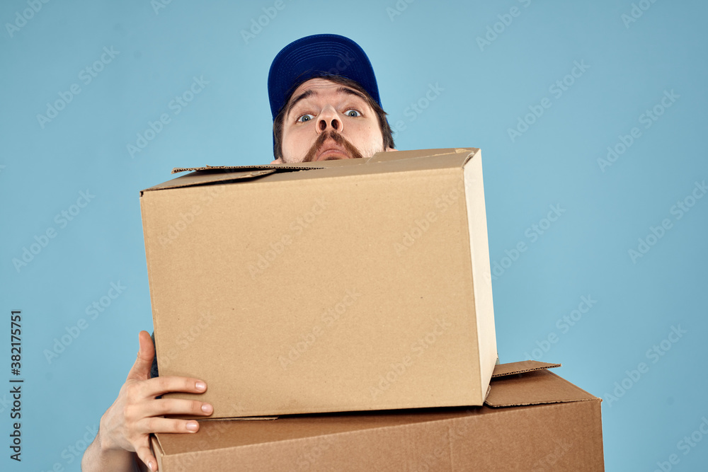 Man in working uniform with boxes in hands delivery service blue background Man in working uniform with boxes in hands delivery service blue background