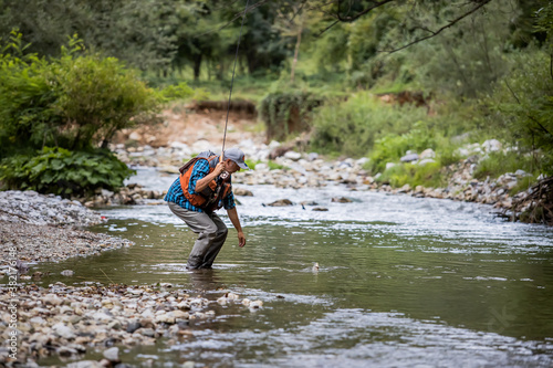 A fly fisherman fishing a trouts in mountain river