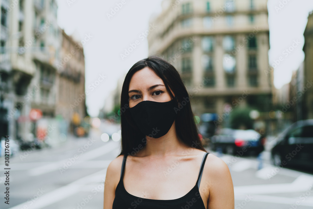 Portrait of a young girl wearing protective sterile medical mask on her face while standing on a street. Pretty caucasian woman in a mask standing on an empty city street background during quarantine Portrait of a young girl wearing protective sterile medical mask on her face while standing on a street. Pretty caucasian woman in a mask standing on an empty city street background during quarantine