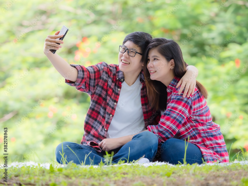 Asian female couples LGBT sitting and take a photo in the garden and embrace each other in love and happiness Asian female couples LGBT sitting and take a photo in the garden and embrace each other in love and happiness