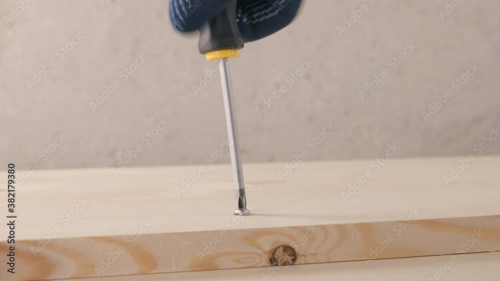 a builder twists and unscrews a screw into a pine wood plank
a builder twists and unscrews a screw into a pine wood plank