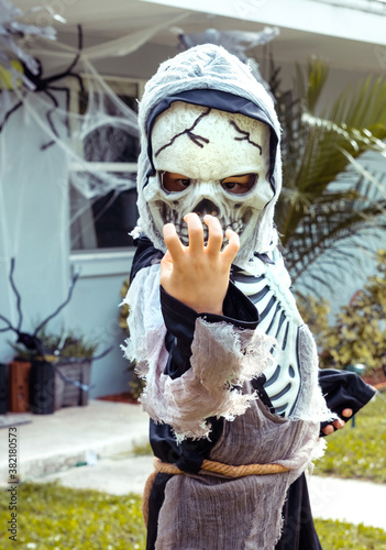 Child in Halloween costume. Little boy in scary skeleton costume trick or treat on street. 
