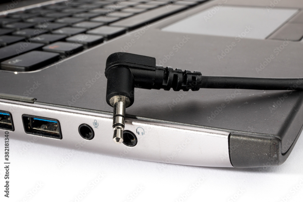 macro closeup of a right angle headphone plug and headphone jack on notebook computer