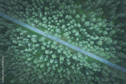 Empty road going diagonally through the forest top down aerial view toned image