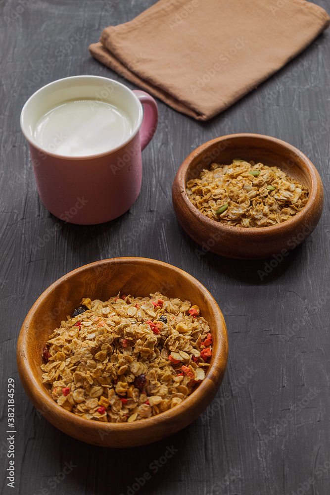 Milk in a purple mug and multi-glaf muesli on a black background Milk in a purple mug and multi-glaf muesli on a black background