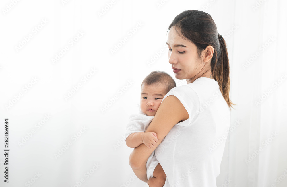 Pretty asian woman holding a newborn baby in her arms. Happy family. Laughing mother lifting her adorable infant baby son on white. Pretty asian woman holding a newborn baby in her arms. Happy family. Laughing mother lifting her adorable infant baby son on white.