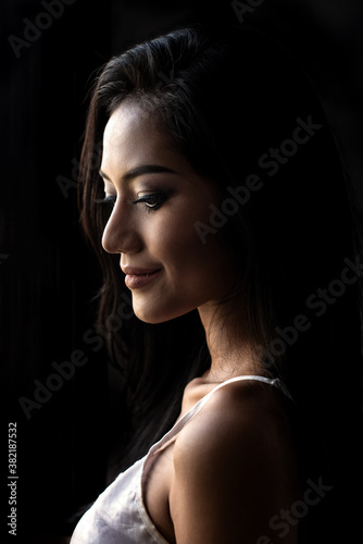 Asian woman in nightgown on dark background. She smile and happy. Close up portrait head shot of the face of a beautiful asia young girl and attractive isolated on black. 