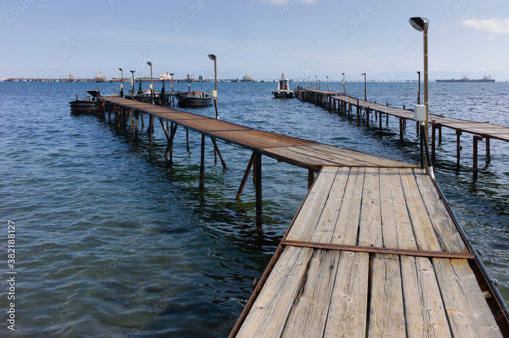 Wooden boat dock in the harbor of  Cagliari with bridge and industry in background