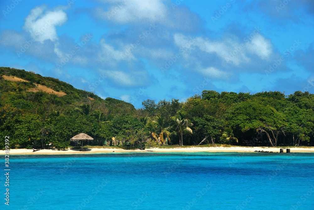 malownicza karaibska wysepka Petit Saint Vincent w lutym. Widok od strony morza. Biały piasek, błękitna woda dużo zieleni