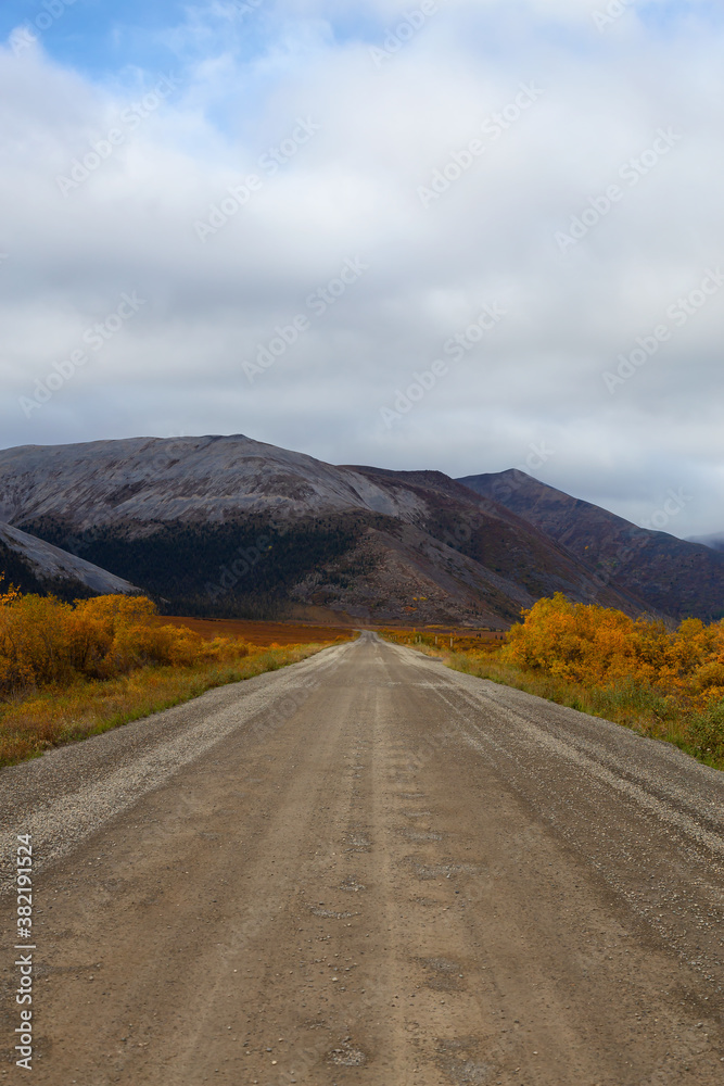 View of Scenic Road and Mountains on a Fall Day in Canadian Nature. Taken near Tombstone Territorial Park, Yukon, Canada. View of Scenic Road and Mountains on a Fall Day in Canadian Nature. Taken near Tombstone Territorial Park, Yukon, Canada.