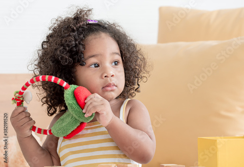 African little black girl playing ear muff in color of christmas in living room © Ann Rodchua