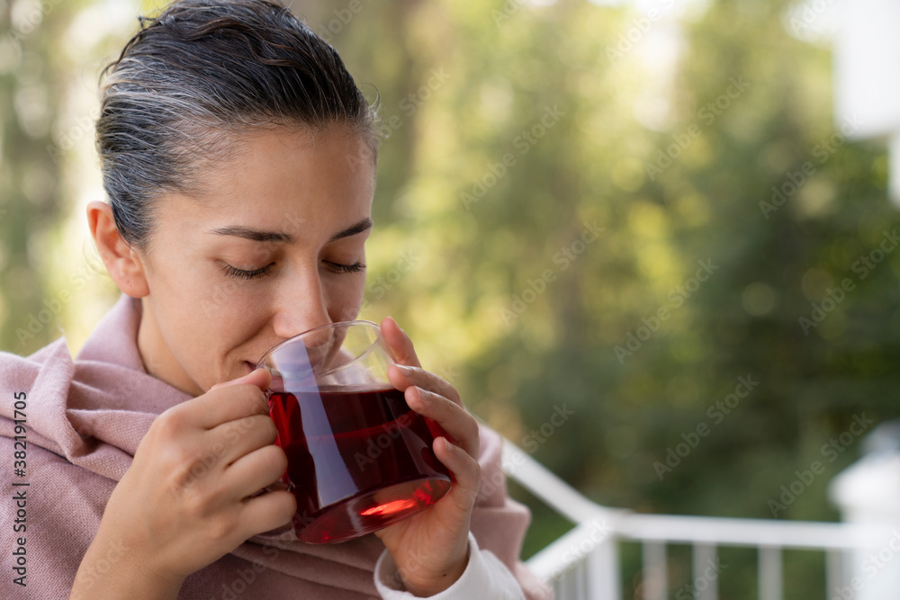 woman wrapped in blanket drinking hot brewed red tea. Tea for immunity, ingredients for the treatment of colds. woman wrapped in blanket drinking hot brewed red tea. Tea for immunity, ingredients for the treatment of colds.