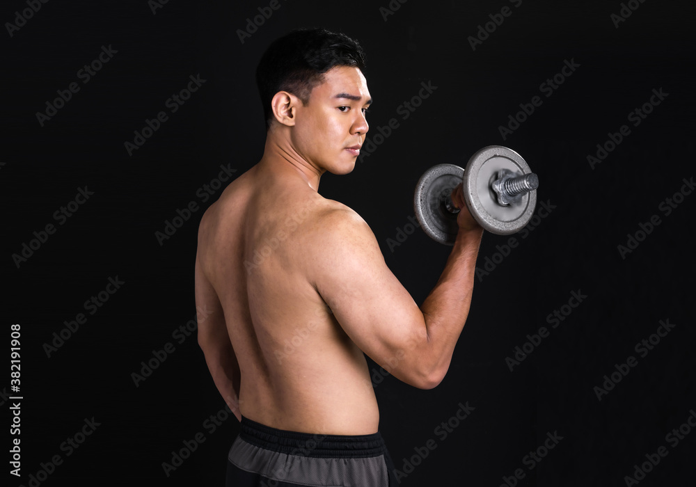Portrait of asian muscular man standing and lifting dumbbell on black background Portrait of asian muscular man standing and lifting dumbbell on black background