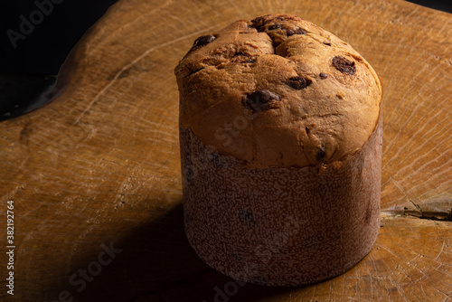 Panettone with chocolate chips on rustic wood with black background, selective focus.