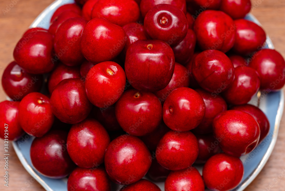 red fresh cherries in a plate on a wooden background red fresh cherries in a plate on a wooden background