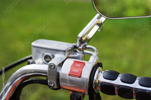 Right handle controls of classic motorcycle with chrome steering wheel and mirrors. Selective focus on start-stop button