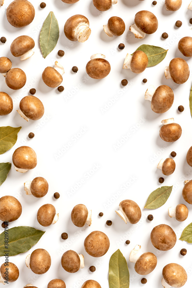 Lots of brown champignons, bay leaves and peppers on a white background top view. Flat lay. Free space for text. Pattern of brown mushrooms and spices. Mushroom cooking