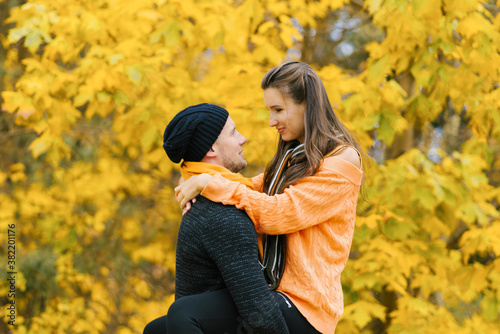 A couple in love embraces each other in the autumn forest. A young man and a girl are walking, a guy is holding a girl in his arms. Travel in the autumn time of the year, at weekends.