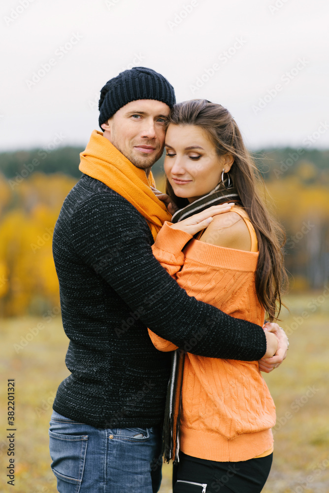 Fototapeta premium A young pretty woman hugs her boyfriend in the fall outdoors. Lovers walk in the Park. Cute lovers in the Park. The family concept. happy couple.