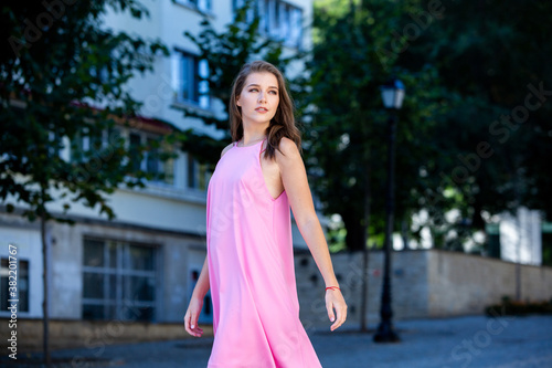 Beautiful european girl in summer dress walking on the street. Sexy young woman in red dress.