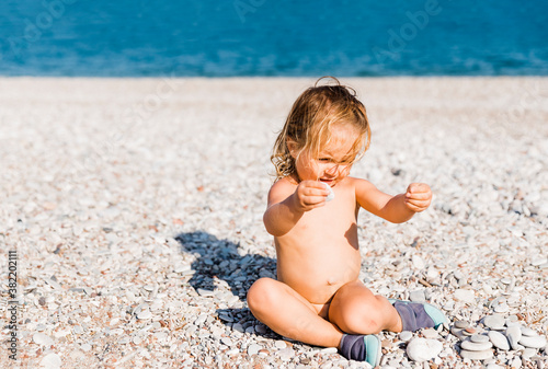 Toddler girl playing with pebbles on beach