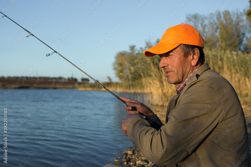 Fishing rod wheel closeup, man fishing with a beautiful sunset. Fishing rod wheel closeup, man fishing with a beautiful sunset.