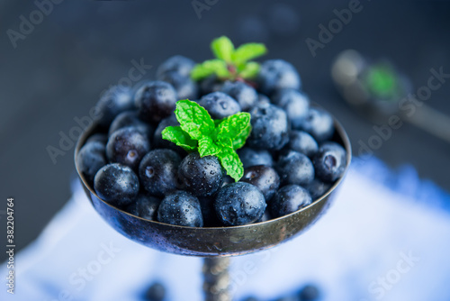 Wallpaper Mural Top view blueberries in vintage metal bowl decorated with mint leaves on the blue napkin on a black wooden background. Dark mood photo. Vertical card. Selective focus, copy space. Torontodigital.ca