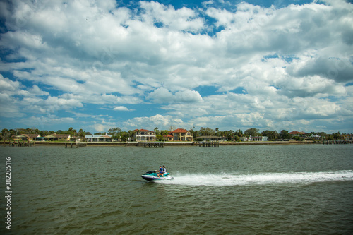 St Augustine, Florida - 2/27/2018: Homes and other buildings on the shoreline that border the harbor at St Augustine, Florida.  A speeding personal watercraft in forgeround. photo