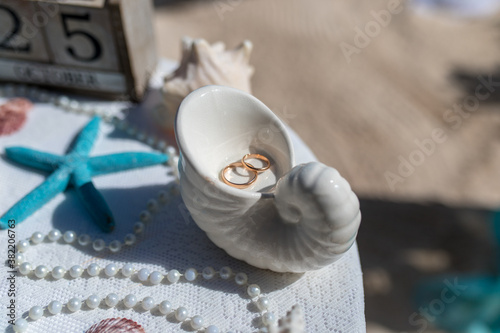 Fotografie Close up view of wedding rings in the white ceramic shell on the table with wedd