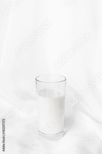 glass of milk on white fabric background, vertical orientation