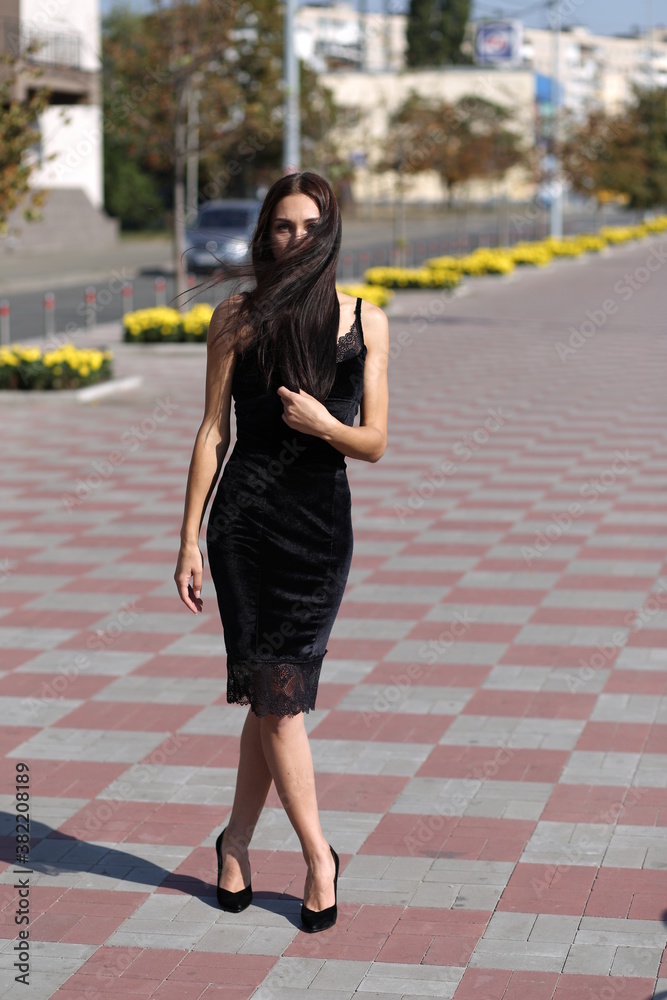 young girl in a black dress walking in the city