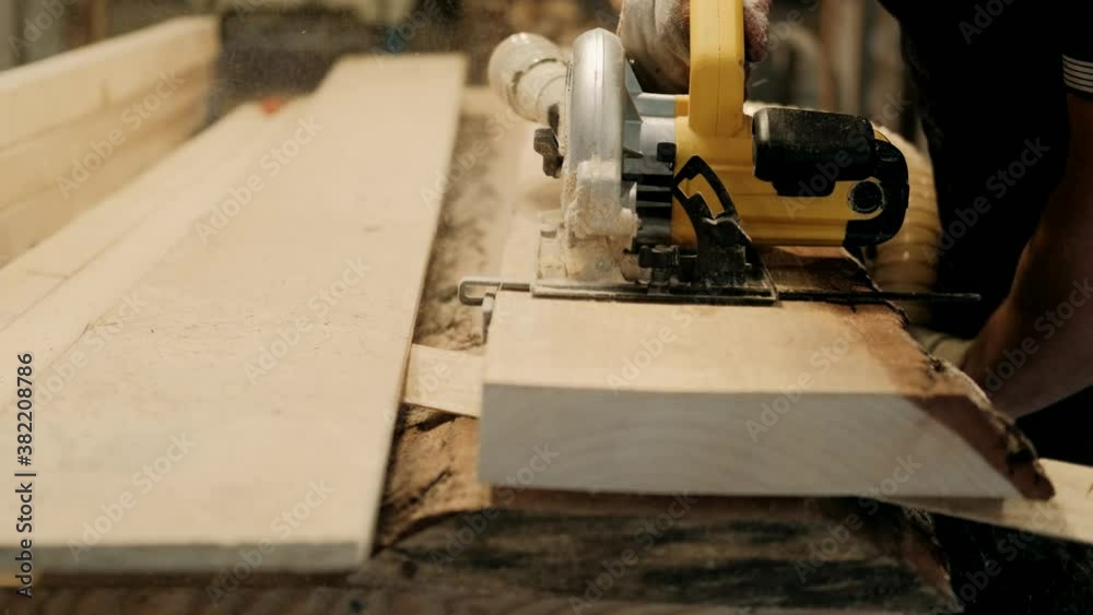 A carpenter processes a wooden blank on a circular saw in a carpentry workshop. Profession, carpentry, woodwork and people concept A carpenter processes a wooden blank on a circular saw in a carpentry workshop. Profession, carpentry, woodwork and people concept