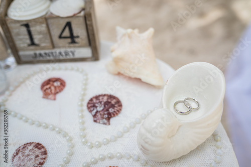 Fotografie Close up view of wedding rings in the white ceramic shell on the table with wedd