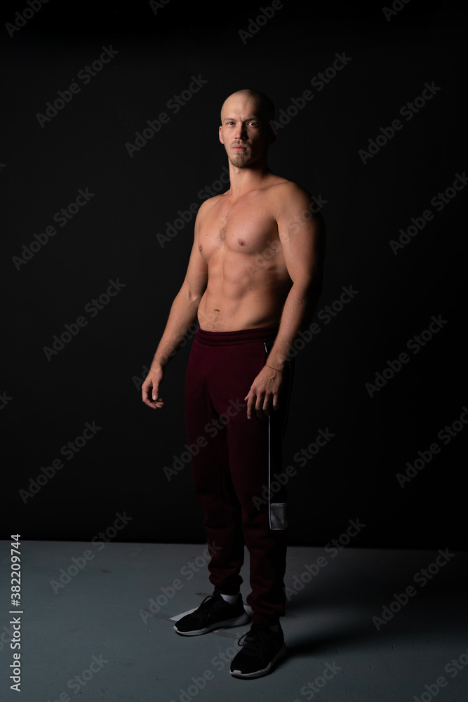 Naklejka premium Serious Russian guy pumped sports Caucasian stands on a black background