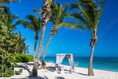 Wedding bamboo gazebo  decorated with tropical flowers and coloured fabrics on the paradise beach with palm trees  white sand and blue water of Caribbean Sea  Punta Cana  Dominican Republic 